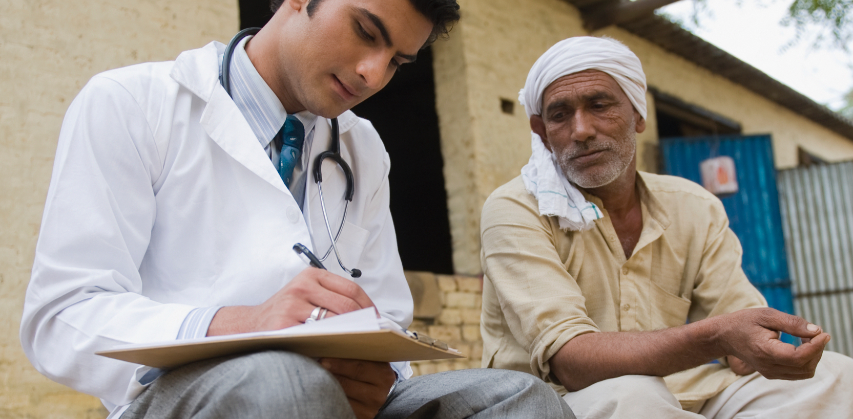 A doctor consulting with patient and writing down notes outside on a curb
