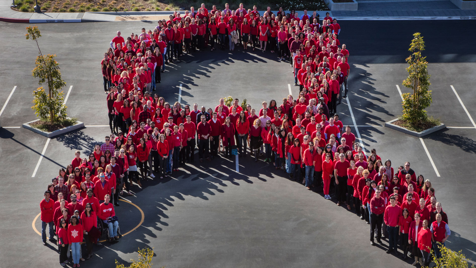 Group of people forming the HIV awareness red ribbon